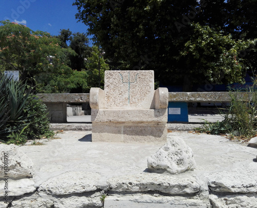 Alone gray stone chair by the sea with Neptune's trident inlay