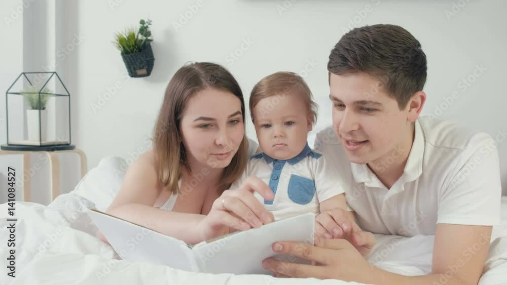 happy loving family. pretty young mother and ded reading a book to her daughters happy loving family. pretty young mother and ded reading a book to her daughters