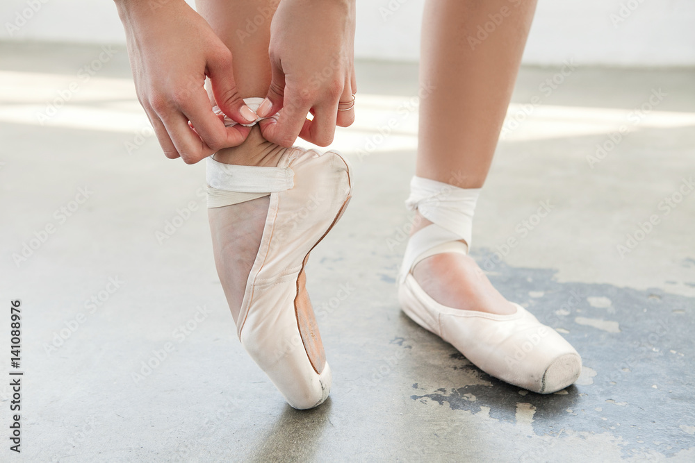 Close up of ballerina tighten the pointes in a dancing studio