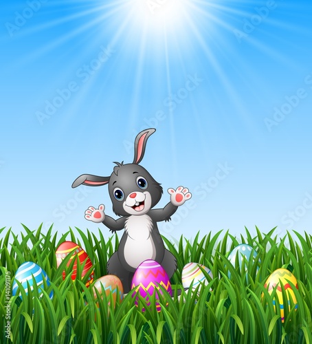 Easter bunny cartoon with Easter eggs in the grass on a background of bright sunshine