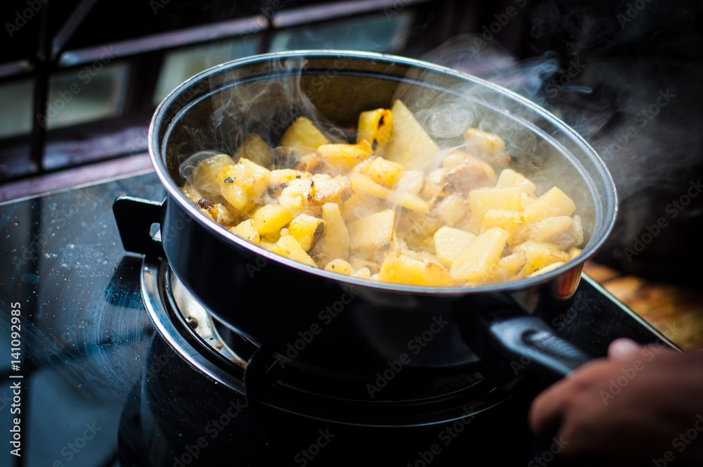 Cooking fried sliced potato in pat with oil