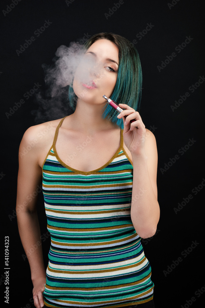 Obraz premium Jeune femme vape une cigarette électronique