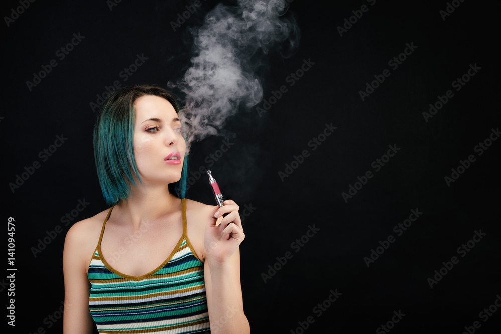 Obraz premium Jeune femme vape une cigarette électronique