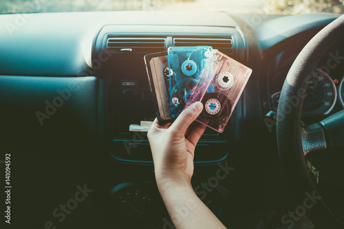 Woman hand holding tape cassette in car for driving listen music - vintage color tone effect.