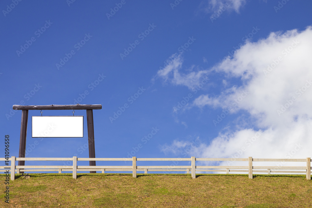 signboard and wood fence with grass and blue sky