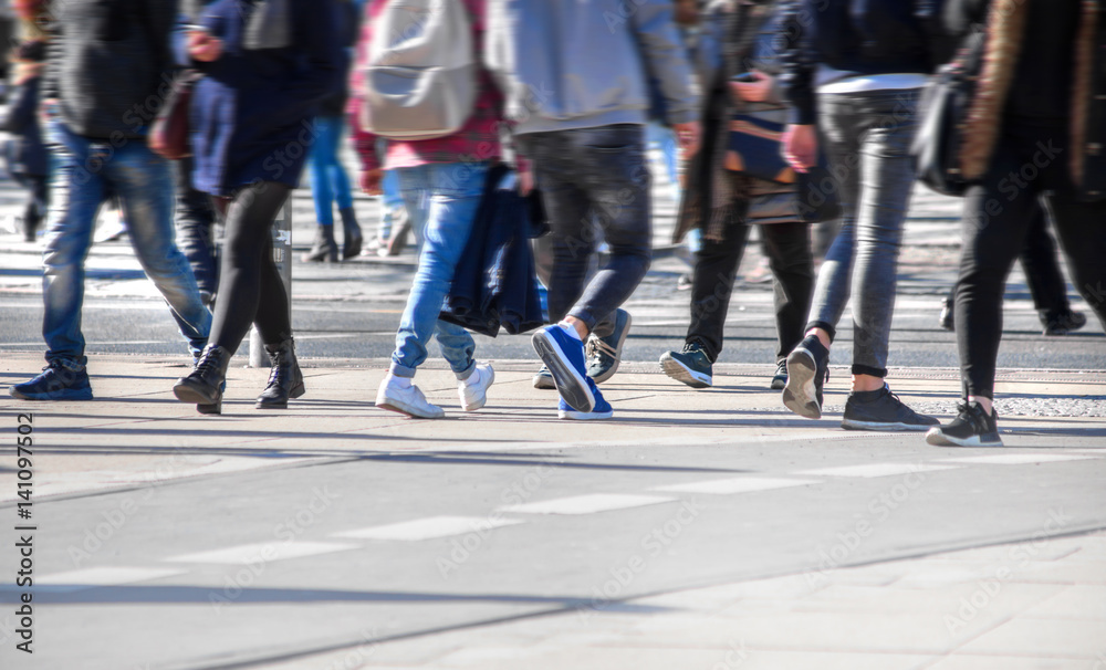Many pedestrians cross a street in a city Many pedestrians cross a street in a city
