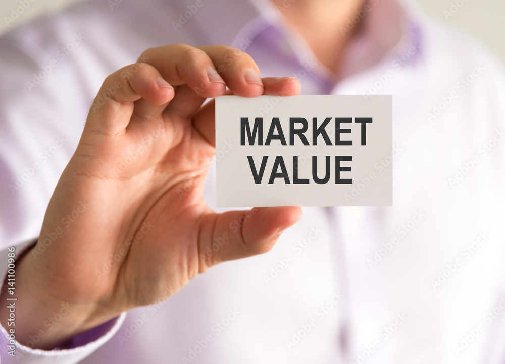 Businessman holding a card with MARKET VALUE message Businessman holding a card with MARKET VALUE message