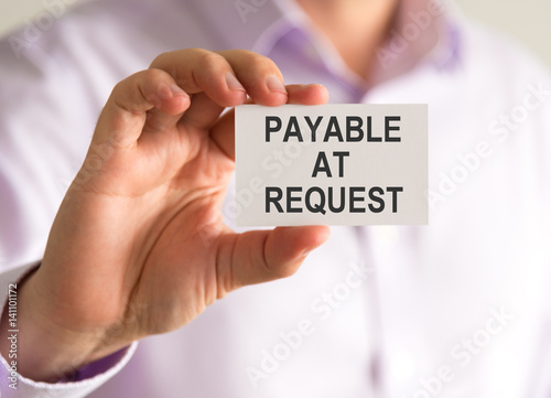 Businessman holding a card with PAYABLE AT REQUEST message