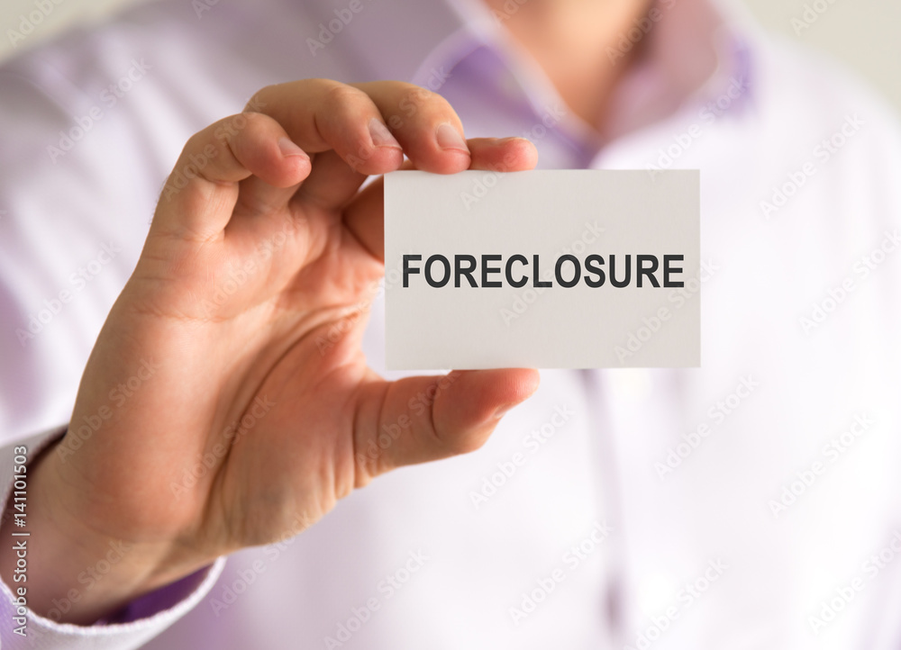 Businessman holding a card with FORECLOSURE message Businessman holding a card with FORECLOSURE message
