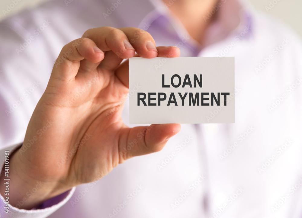 Businessman holding a card with LOAN REPAYMENT message Businessman holding a card with LOAN REPAYMENT message
