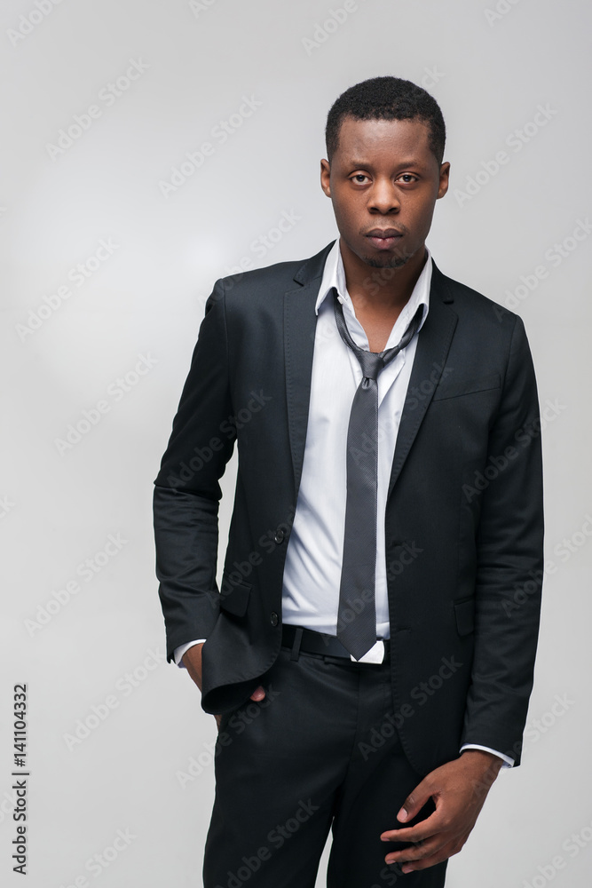 Fashion show, collection of designed clothes. African american guy model in elegant suit on grey background with free space.
