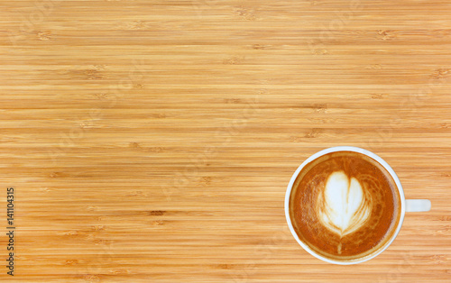 Top view of a coffee with heart pattern in a white cup on bamboo wooden background