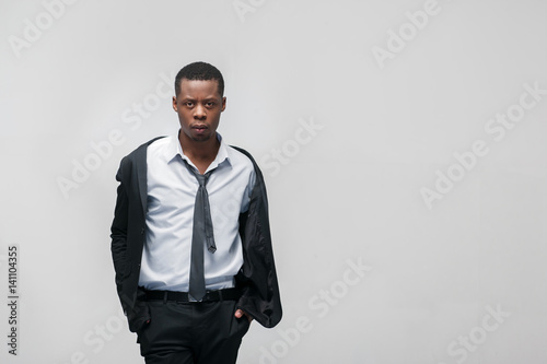 Fashion show, collection of designed clothes. African american guy model in elegant suit on grey background with copy space.