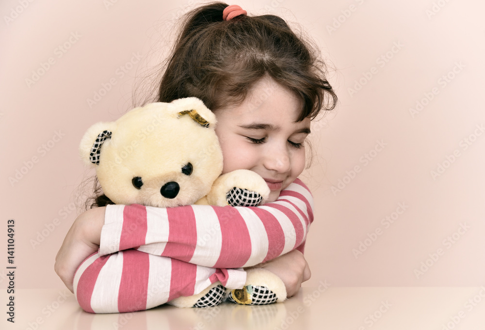 Young girl hugging teddy bear, eyes closed, Stock image