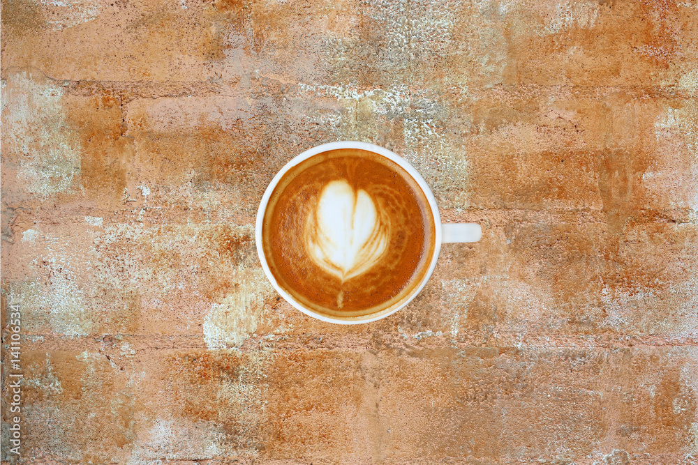 Top view of a coffee with heart pattern in a white cup on rusty cement background, latte art