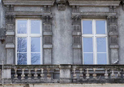 Two vintage front glass windows with a balcony of an old house