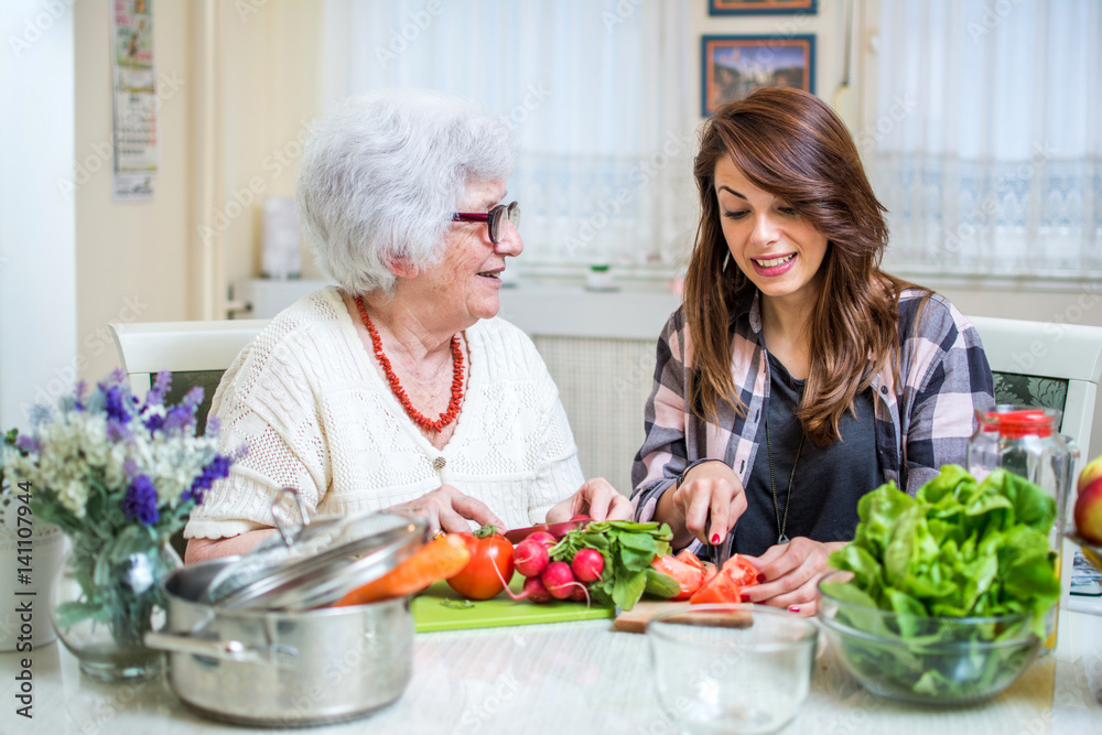 Grandmother and her granddaughter preparing healthy food together in the kitchen. Grandmother and her granddaughter preparing healthy food together in the kitchen.
