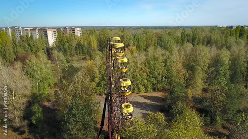 Panning orbit around abandoned ferris wheel of Pripyat Town after meltdown of Chernobyl nuclear power plant in 1986. Reactor & new sarcophagus are seen on the horizon. Oct 2016. photo