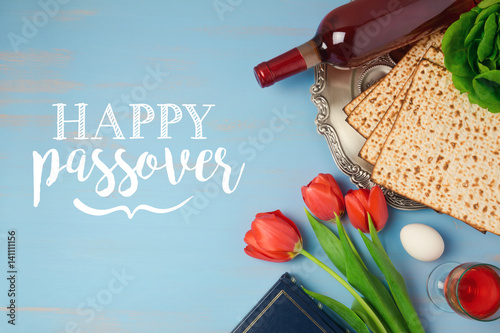 Jewish holiday Passover Pesah greeting card with seder plate, matzoh and tulip flowers on wooden background