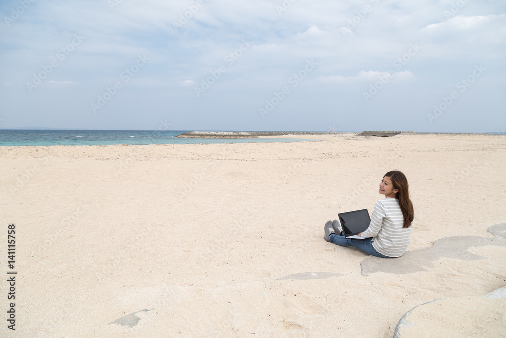 ビーチの若い女性とノートパソコン