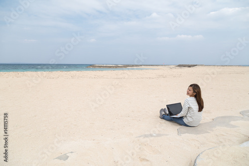 ビーチの若い女性とノートパソコン
