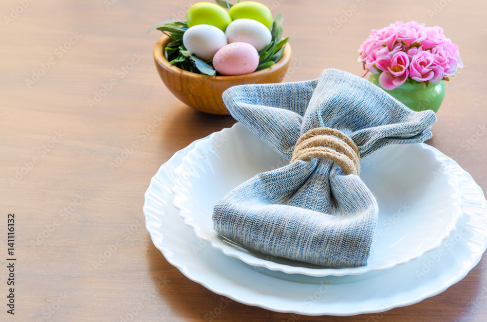 Easter place setting en white blue tone. Plate, cutlery and line napkin, colorful eggs and decorative flowers on wooden background. Copy space. Happy Easter concept. Easter place setting en white blue tone. Plate, cutlery and line napkin, colorful eggs and decorative flowers on wooden background. Copy space. Happy Easter concept.