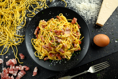 Classic Homemade Pasta carbonara Italian with Bacon, eggs, Parmesan Cheese on black plate. photo