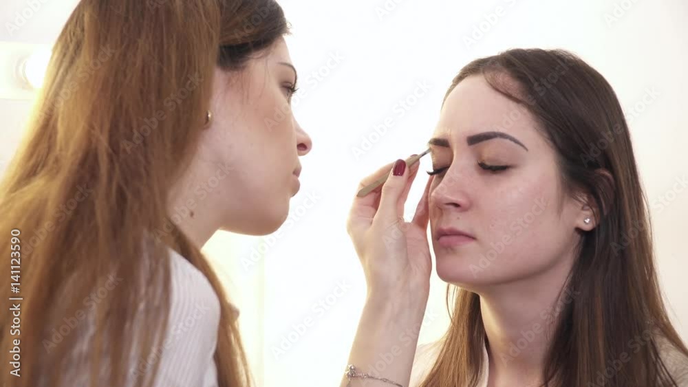 Young makeup artist making makeup for a woman Young makeup artist making makeup for a woman