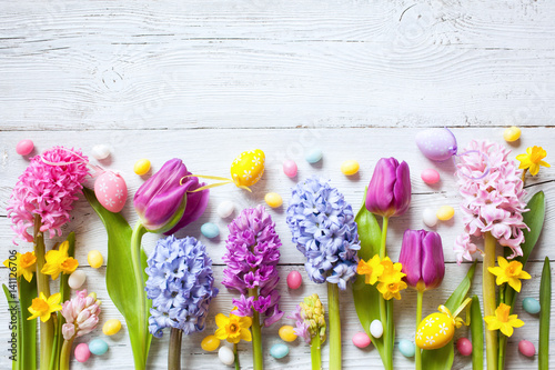  Spring Easter white wooden background with eggs, candies and flowers hyacinths, tulips, space for greeting text