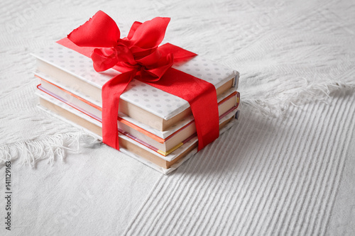 Gift books beautifully wrapped and bandaged with a red ribbon bow on a white coverlet photo