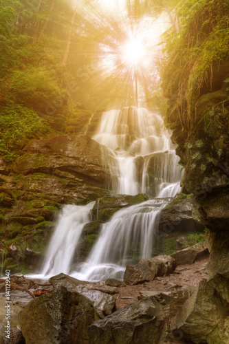 Amazing beauty of Alps mountains waterfall. Summer waterfall in Alps with soft sun rays at evening