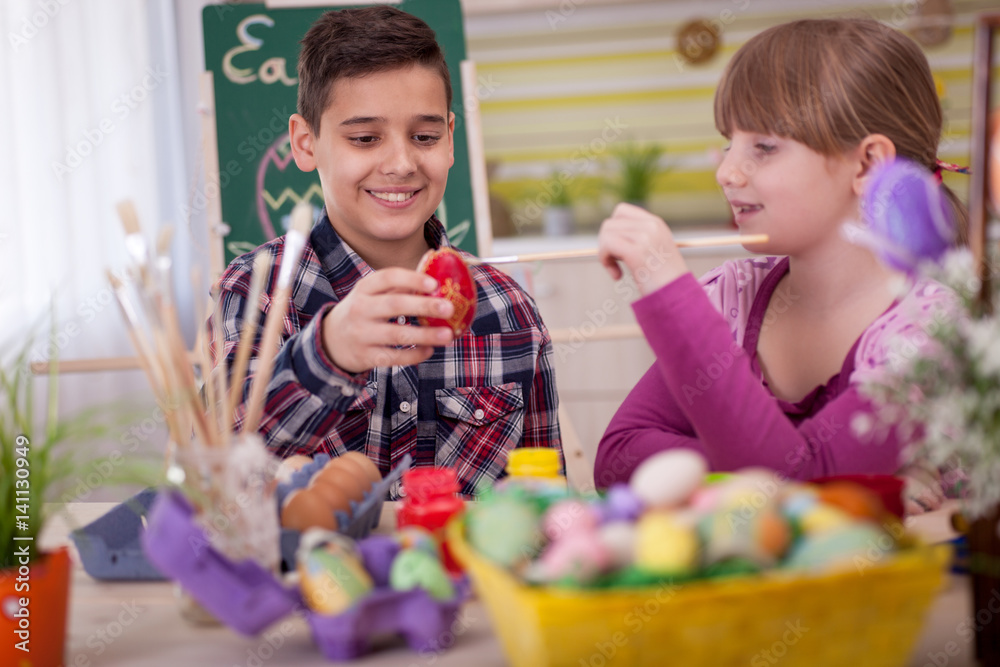 Obraz premium Two smiling kids paint easter eggs