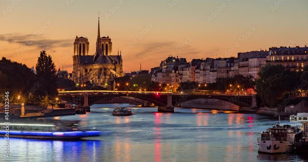 Notre Dame de Paris Cathedral, Ile Saint Louis and the Seine River at twilight. Time lapse of a summer evening with city lights and the Sully Bridge in the 4th Arrondissement of Paris. France