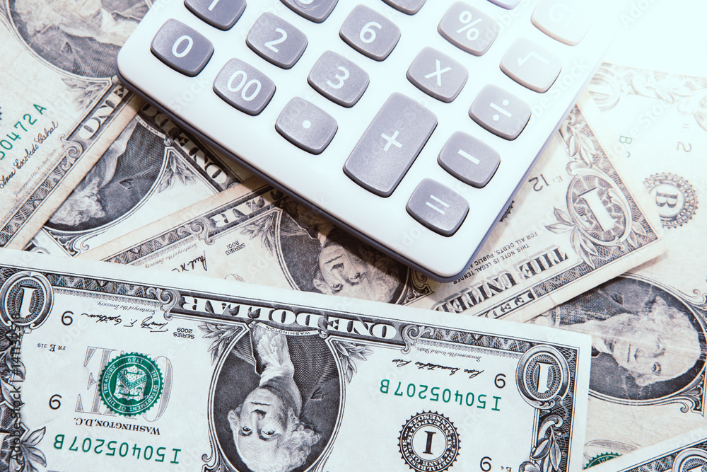 Fototapeta premium Calculator with american dollars on the wooden table background, finance concept