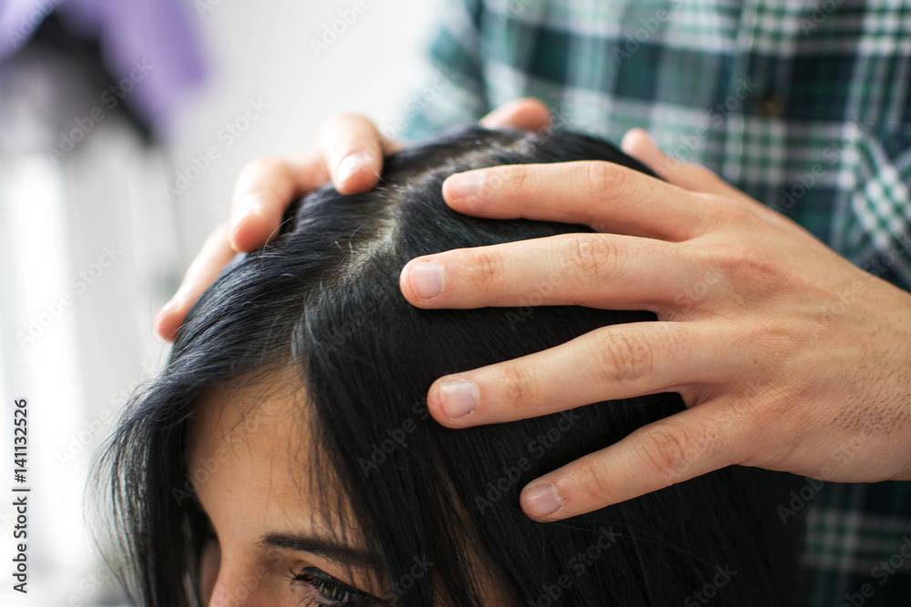 Naklejka premium Close up of hands of hairdresser making hairstyle for customer.