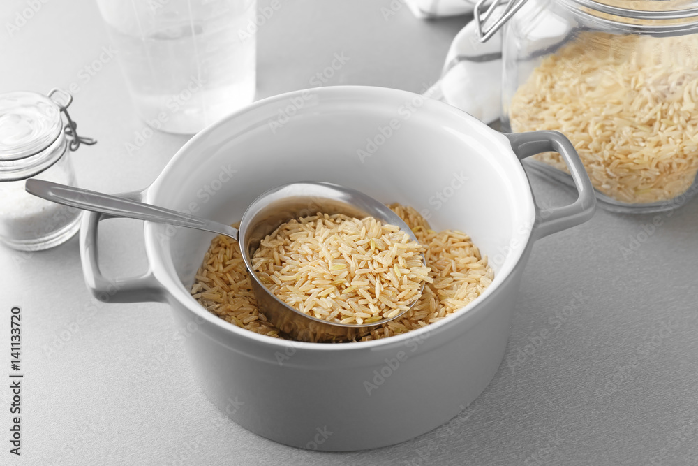 Saucepan with raw brown rice on table Saucepan with raw brown rice on table