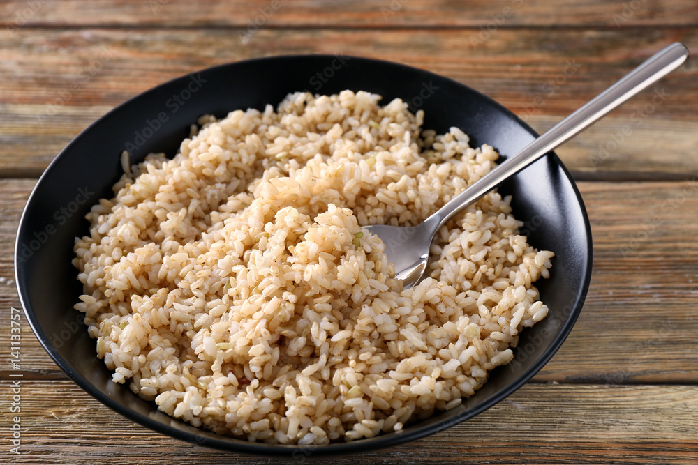 Plate with brown rice on wooden table background Plate with brown rice on wooden table background