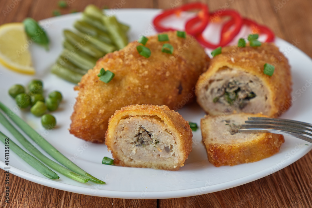 Chicken cutlets with mushrooms and vegetables on a wooden background