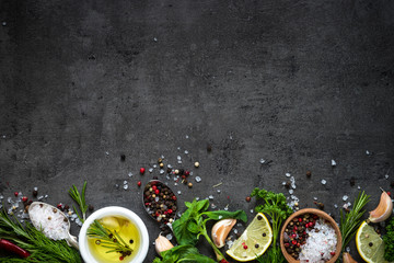 Selection of spices herbs and greens. Rosemary basil lemon olive oil pepper top view black background.