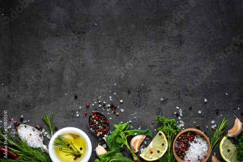Fototapeta Naklejka Na Ścianę i Meble -  Selection of spices herbs and greens. Rosemary basil lemon olive oil pepper top view black background.