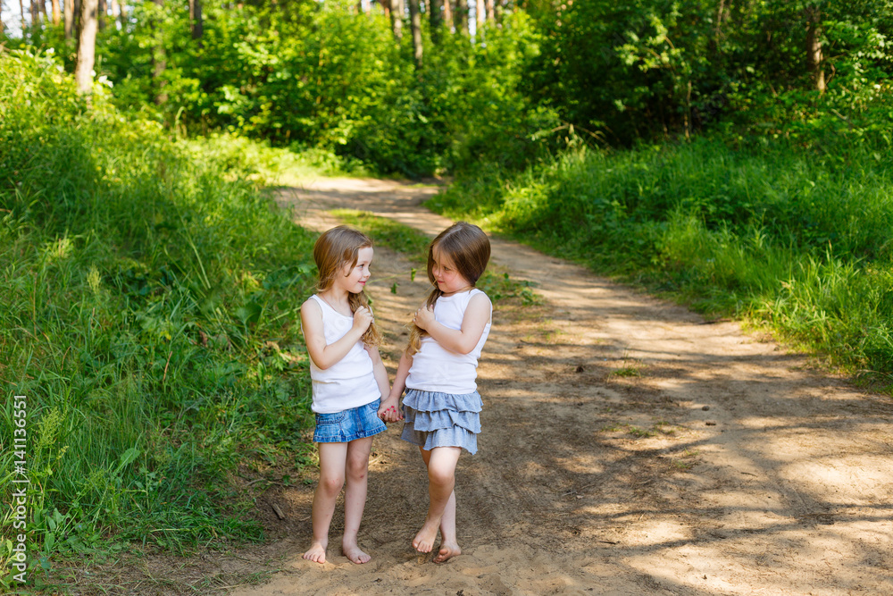 Two little girl girl friends hugging in the forest Two little girl girl friends hugging in the forest
