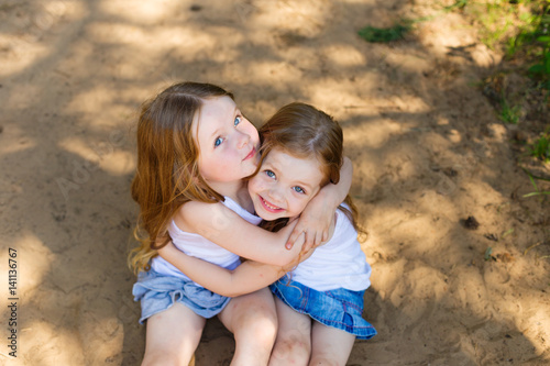 Two little girl girl friends hugging in the forest