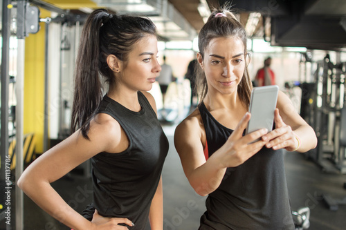 Two female friends taking a selfie photo at gym.
