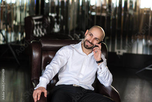 A bald man talking on the phone.