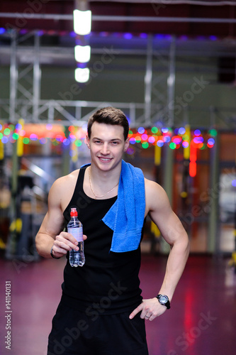 Handsome guy at the gym, drinking water.