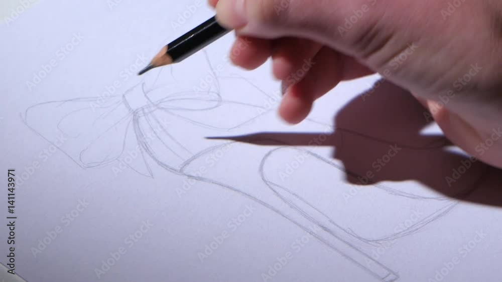 Designer shoes sits in the workplace and create a pencil sketch. Close up