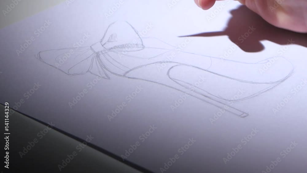 Designer smooth srih draws a sketch of beautiful female shoes. Close up