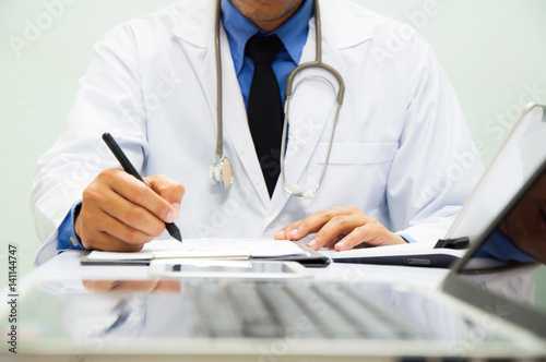 Medicine doctor working with computer notebook and digital tablet at desk in the hospital