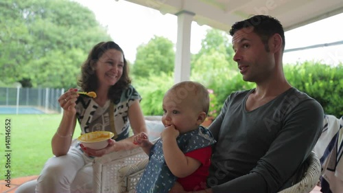 Dad holding his happy month's old son while mom feeds him a healthy nutritonal meal. Baby being fed an afternoon meal photo