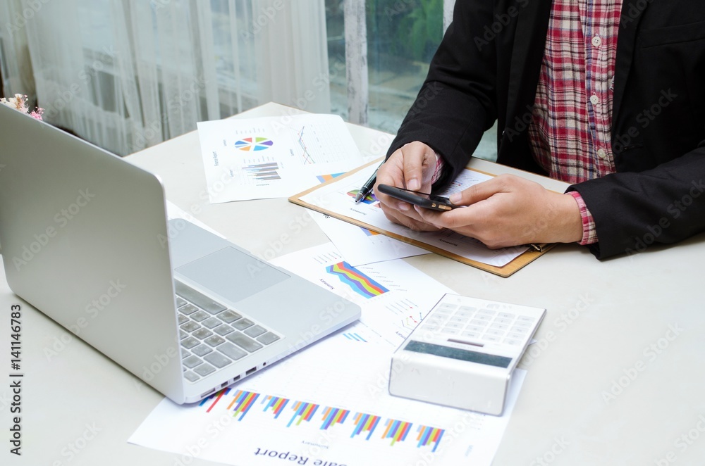 businessman hand working with business document and laptop computer notebook on wooden desk as concept with business and working concept, selective focus and vintage tone, color tone effect